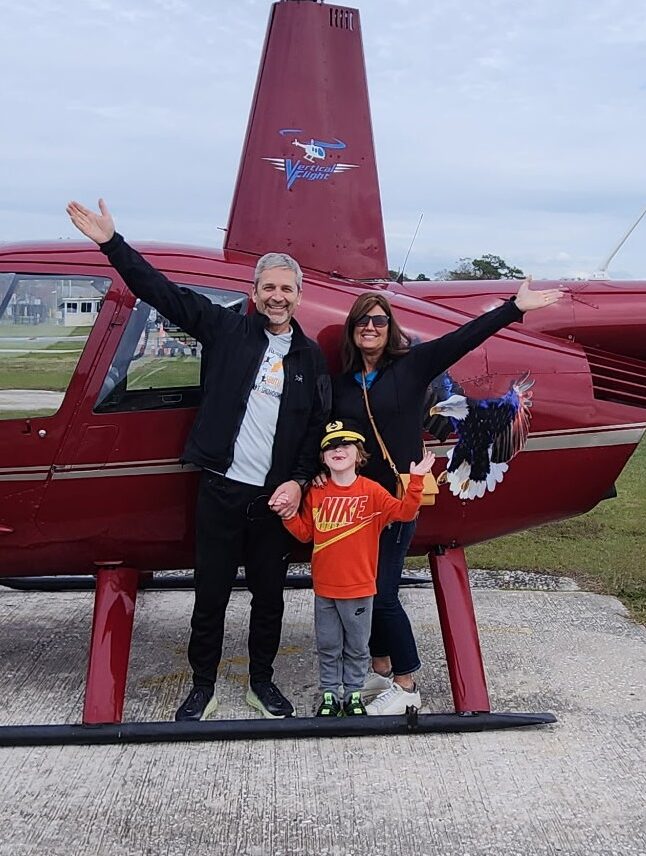 Family posing beside a red helicopter before a flight in Northwest Indiana